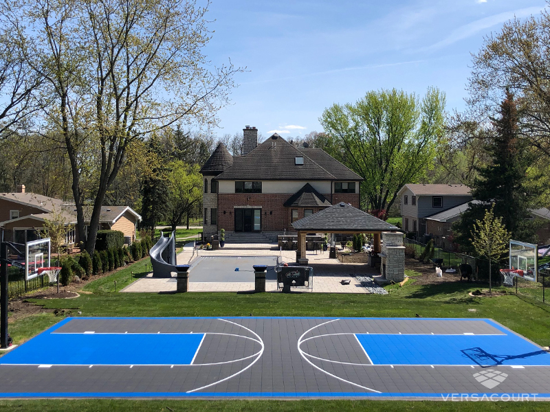 Full length VersaCourt basketball court behind a family home